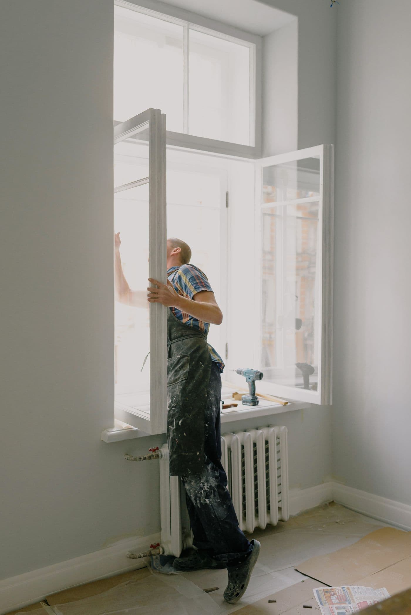 A tradesperson fitting a window frame during a renovation